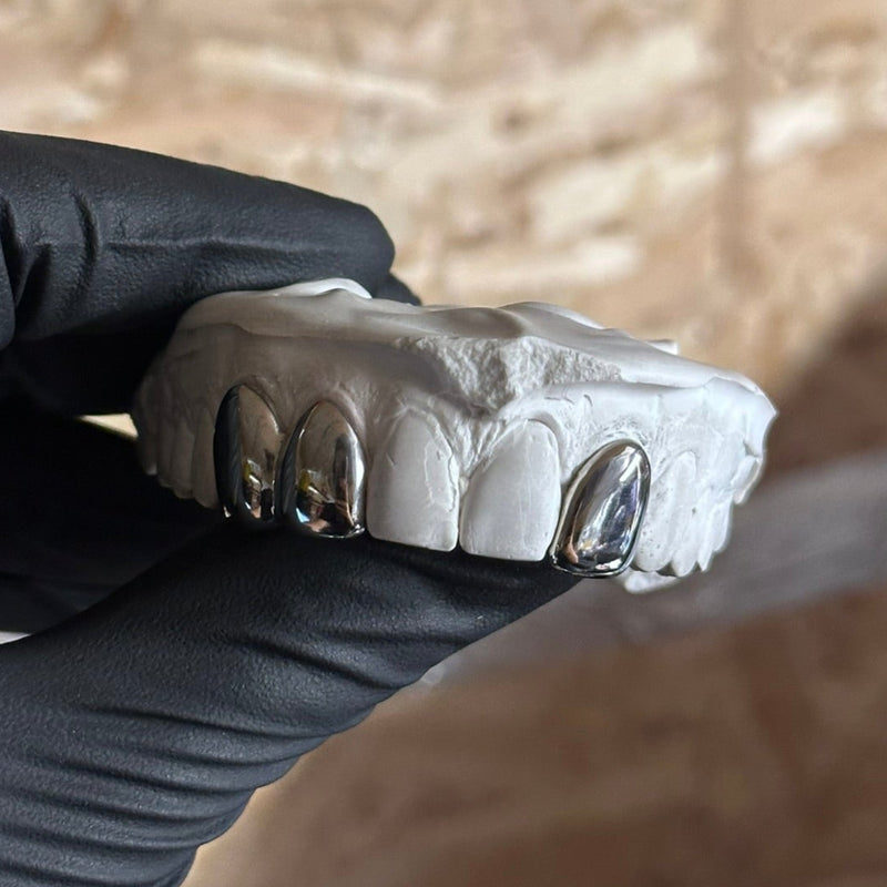 3 dental silver caps being held by black glove 