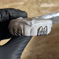 4 dental silver caps on stone model being held by black glove