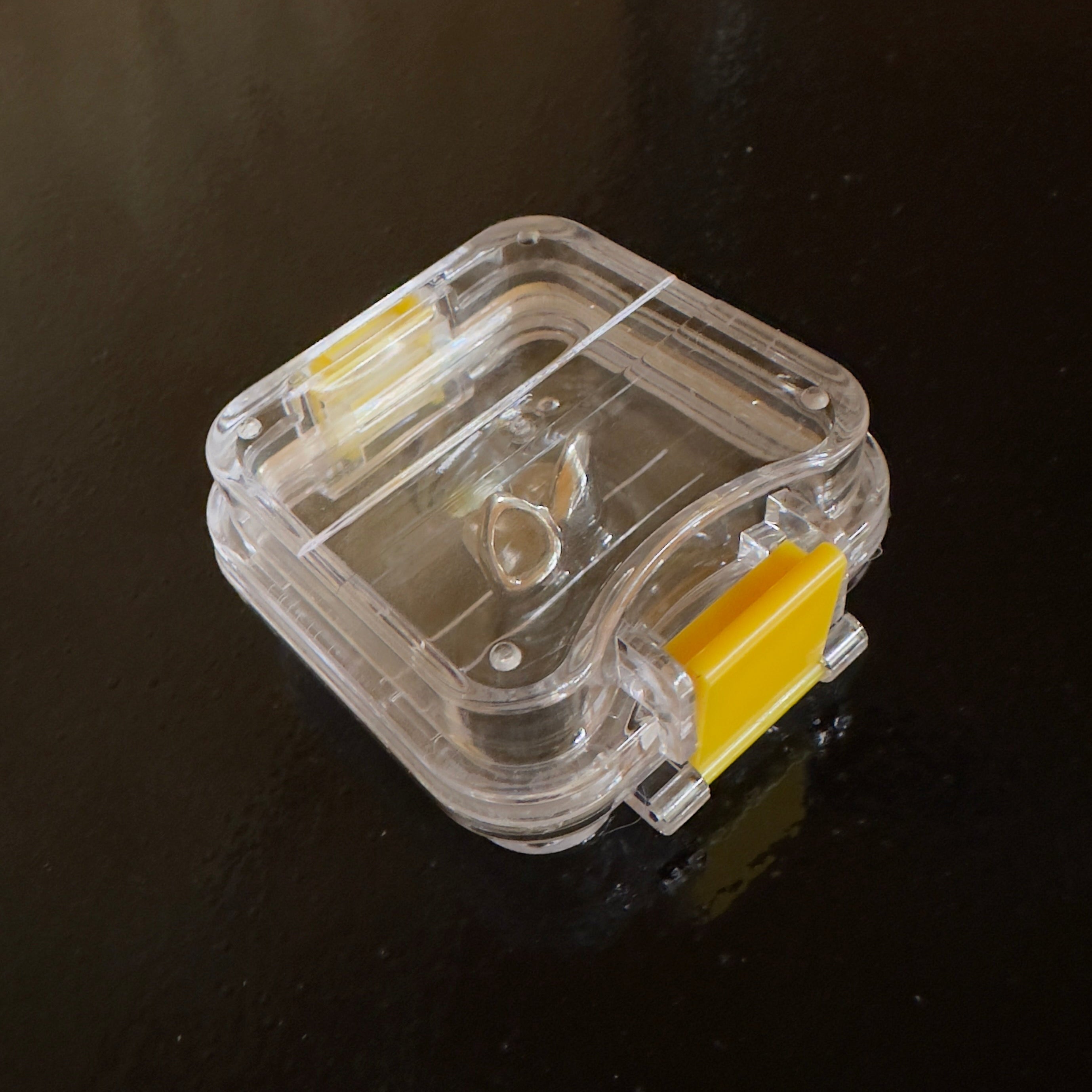 Clear grillz case with yellow clips showcasing some grillz inside on a black table 